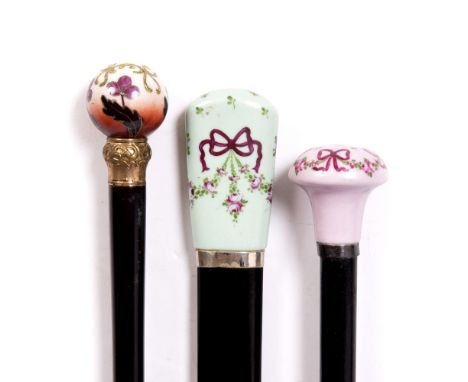 A GROUP OF THREE LATE VICTORIAN SILVER MOUNTED EBONISED WALKING CANES with decorative polychrome ceramic knobs, approximately
