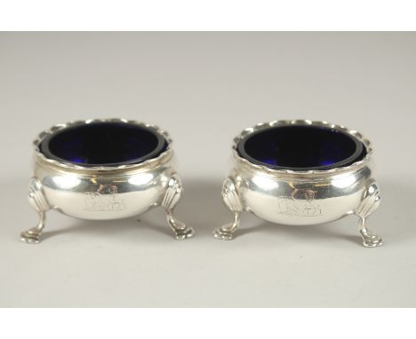 A PAIR OF GEORGE III CIRCULAR SILVER SALTS with sapphire blue liners, on three pad feet. London 1788.