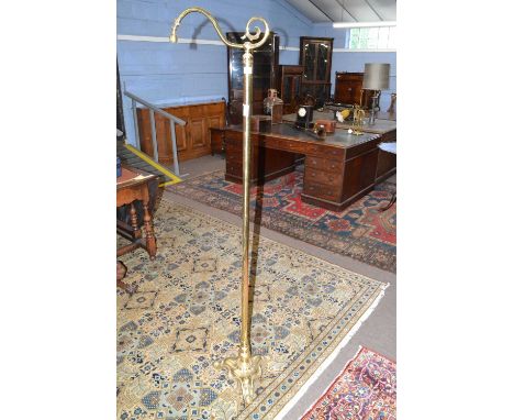 Brass standard lamp with three footed base, plain column and a scroll top, (lacking shade), 172cm high