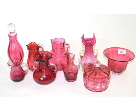 A quantity of Cranberry glass wares Victorian and later comprising; 4 jugs of varied sizes, a Victorian vase with gilt handle