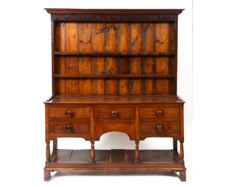An oak and pine dresser, the moulded cornice above a two tier plate rack, the base with an arrangement of five drawers on tur