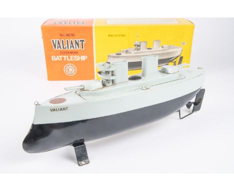 A Sutcliffe Model Valiant clockwork tinplate Battleship. In black and blue-grey. Complete with mast, key and stand. Boxed, so
