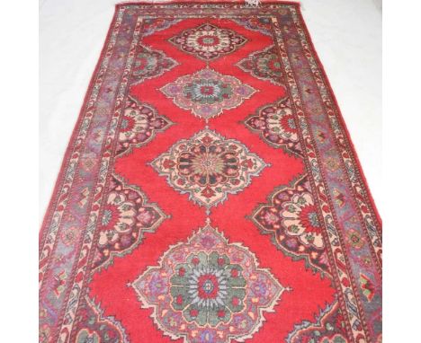 A Persian woollen carpet, 400 x 150cm, with a row of central diamonds, on a red field