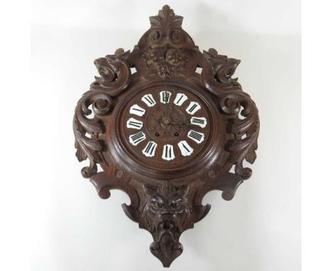 A black forest carved Green Man wall clock, with scrolled decoration, 69cm high