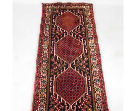 A Persian runner, with a row of three hooked diamonds, on a red ground, 278 x 80cm