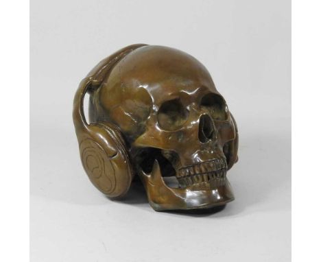 A life sized bronzed skull, wearing headphones, 21cm wide