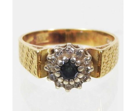 An 18 carat gold, sapphire and diamond cluster ring, with textured shoulders, 3.8g, size K 
