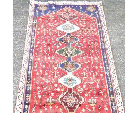 A Persian qashgai runner, with a row of central hooked medallions, on a red ground, 285 x 108cm