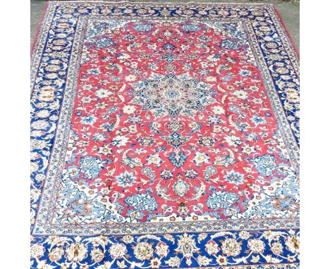 A large Persian Isfahan carpet, with foliate designs, on a red field, 380 x 285cm