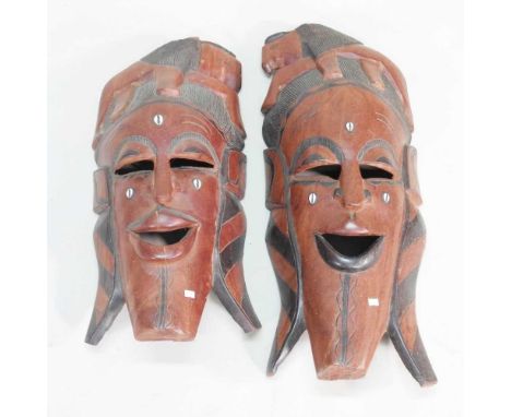 Two similar large African carved hardwood masks, each inlaid with shells, 82 and 71cm high (2)