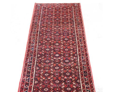 A Persian Malayar runner, with rows of medallions, on a red ground, 375 x 95cm