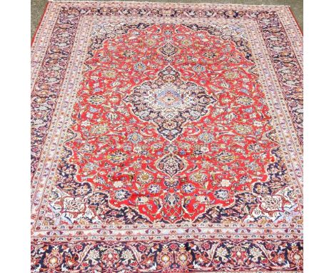 A Persian Kashan carpet, with foliate designs, on a red ground, 405 x 290cm