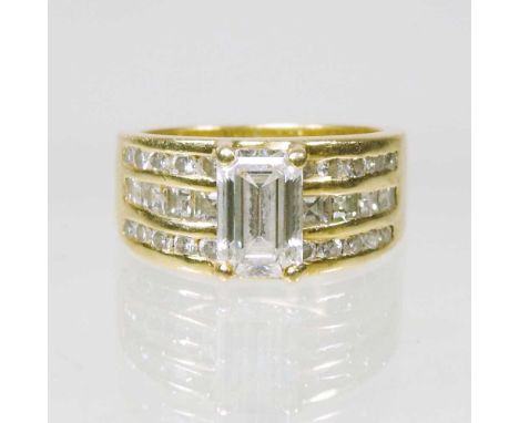 An 18 carat gold and diamond ring, with a central emerald cut stone, approximately one carat, flanked by three rows of channe