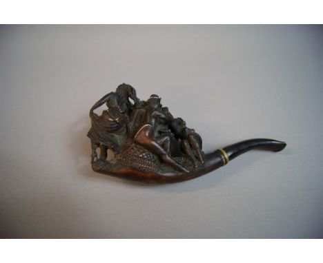 A complex figural carved pipe, possibly meerschaum, the bowl in the form of a basket with foliage, with two men and women in 