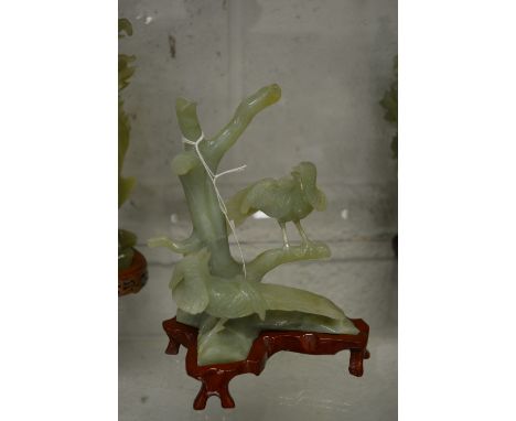 A Chinese carved jade group depicting birds on a branch, on a hardwood stand.