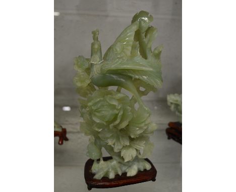 A Chinese carved jade group of a bird on flowering branches on a hardwood stand.