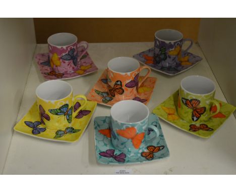 A colourful set of six coffee cans and saucers decorated with butterflies.