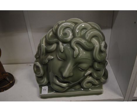 In the manner of Goldscheider, a stylised green glazed pottery mask of Medusa.