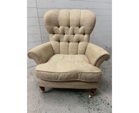 A button back armchair on turned legs and brass wheels