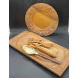 A wooden carved plate along with serving utensils