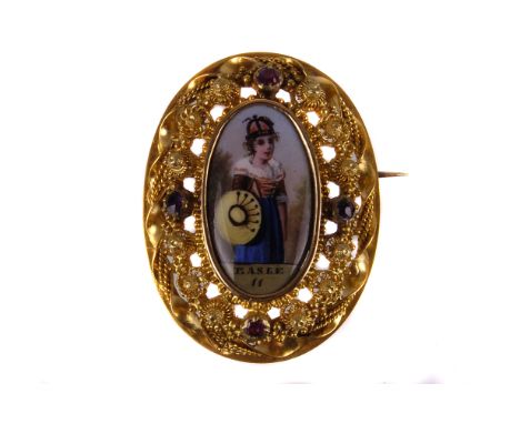 A pretty Edwardian pinchbeck and enamel brooch, the oranate oval pierced mount set with four red cut stones and centred with 