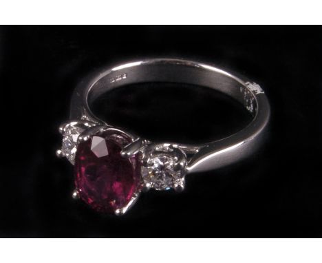 A modern ruby and diamond three stone ring, in 18ct white gold mount having central oval cut ruby of approx 1.8ct and flanked