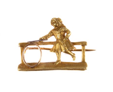 A late 19th century French gold novelty brooch, modelled as a young girl playing with a hoop, marked to pin, in associated ca