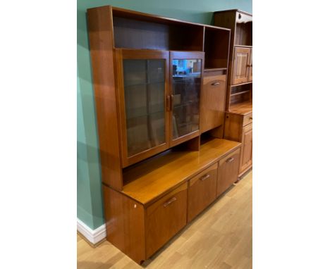 A mid 20th century teak wall/display unit, with twin glazed door cupboards and fall front mirrored compartment with fitted sh