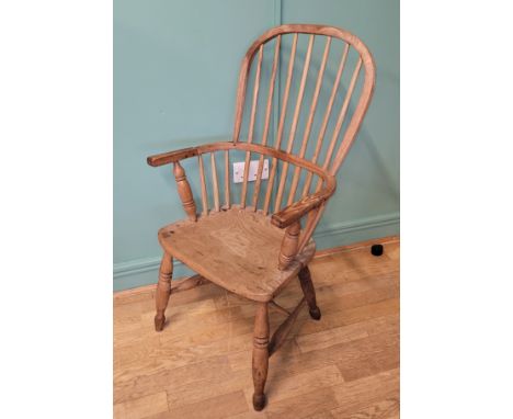 An early 20th century Windsor chair, high hoop and stick back over shaped saddle seat, raised on ring turned supports united 