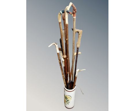 A ceramic stick pot containing assorted walking sticks including deer's hoof and antler handled examples and a huntsman's whi