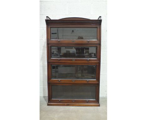 A mahogany four-tier Globe Wernicke-style sectional bookcase with dentil frieze above four bevelled glazed up-and-over doors,