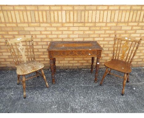 A highly carved console table, approximately 73 cm x 94 cm x 46 cm and two kitchen chairs. [3]