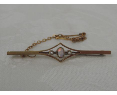 A yellow metal bar brooch stamped 9ct having a central opal flanked by two seed pearls,  approx 3.4g