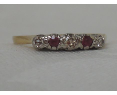 A ladies dress ring having two rubies interspersed by three diamonds in a gallery mount on a yellow metal loop stamped 18ct, 