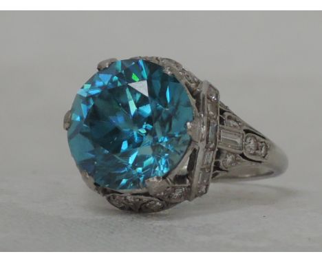 A ladies dress ring having a blue topaz solitaire in raised mount set with diamonds on a white metal loop, no marks possibly 