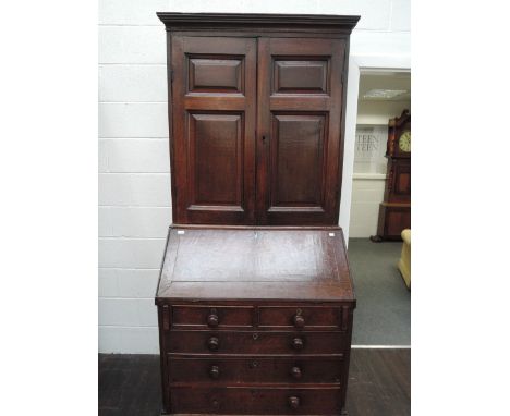 An early 19th century George III oak bureau bookcase having panelled top over slope front and cockbeaded drawer base on brack