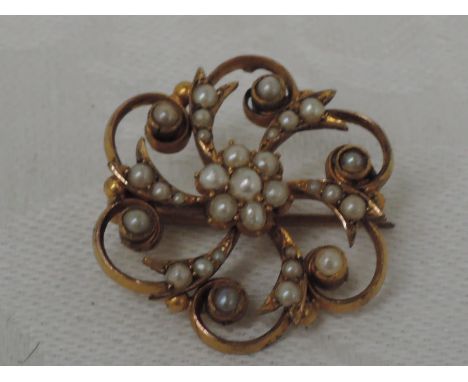 An Edwardian style yellow metal floral shaped brooch stamped 15ct having seed pearl decoration