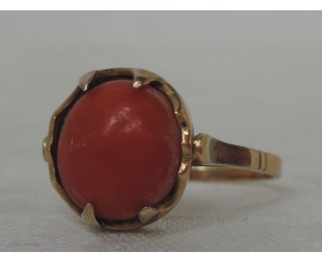 A ladies dress ring having a coral cabouchon stone in a claw setting on a yellow metal loop, no marks tested as 15ct gold,  s