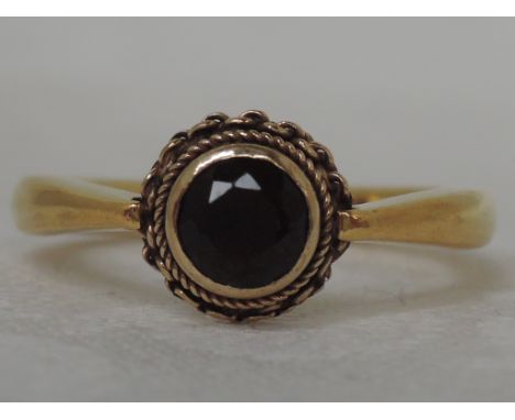 A Victorian ladies dress ring having a circular garnet in a collared mount with chain decoration on a 22ct gold loop, Chester