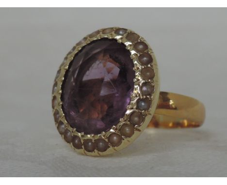 A ladies dress ring having an oval amethyst stone within a seed pearl border in a covered mount bearing marks, on a yellow me