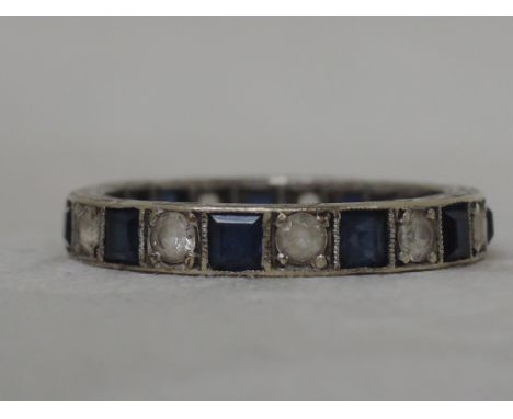 A full eternity ring set with square sapphires interspersed by spinnels in a white metal loop stamped 9ct