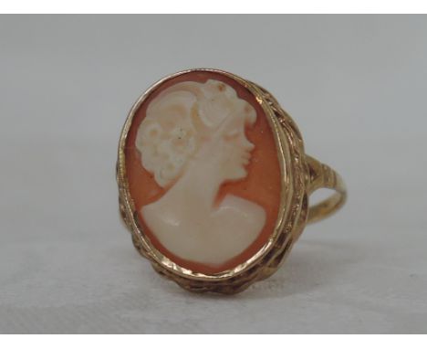 A ladies dress ring having a conche shell cameo depicting a maiden in profile in a collared mount to open shoulders on a 9ct 