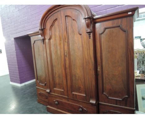 A Victorian mahogany wardrobe having arch breakfront door with drawer under, flanked by further doors, with fitted interior i