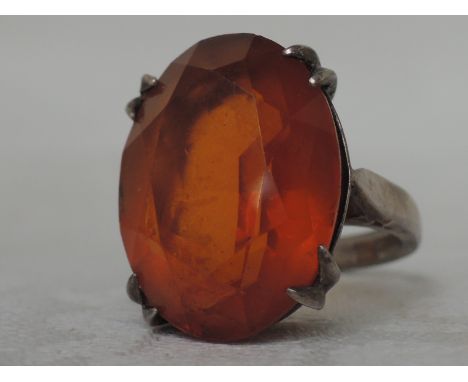 A ladies dress ring having a large citrine style stone in a raised basket claw mount on an HM silver loop