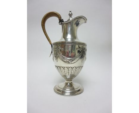 "A George III silver Wine Jug of urn shape embossed ribbons and swags above leafage frieze, cane handle on beaded circular ba