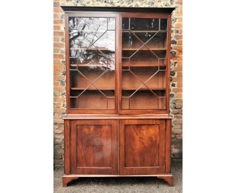 A George III mahogany bookcase cabinet with a moulded cornice, over a pair of astragal glazed doors, enclosing three height a