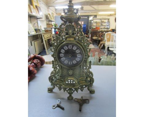 An ornate brass cased mantle clock, the dial with white enamelled and black painted roman numerals, battery operated movement