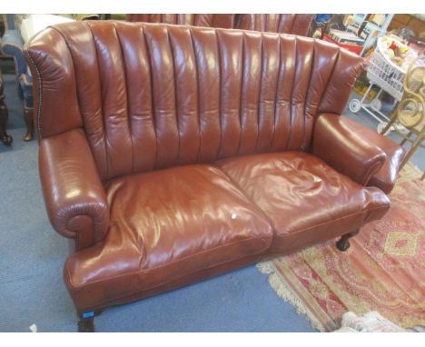 A leather two-seater sofa and two armchairs with foot stools on ball and claw feet 