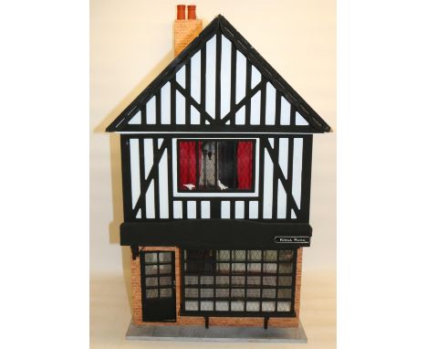 Tudor style three-room dolls house, comprising ground floor shop front, room above, and attic room, with wall and floor cover