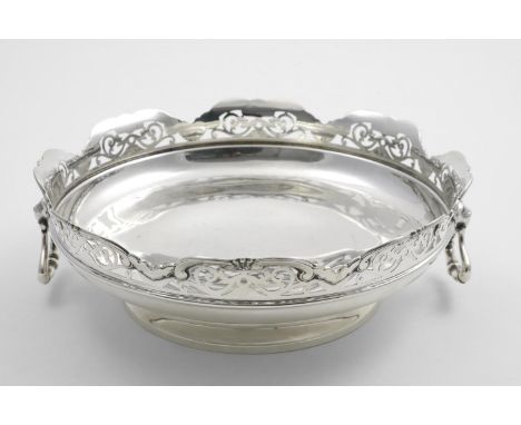 AN EDWARDIAN SHALLOW CIRCULAR FRUIT DISH with a shaped and fret-pierced rim and two cast lion-mask and drop ring handles, by 